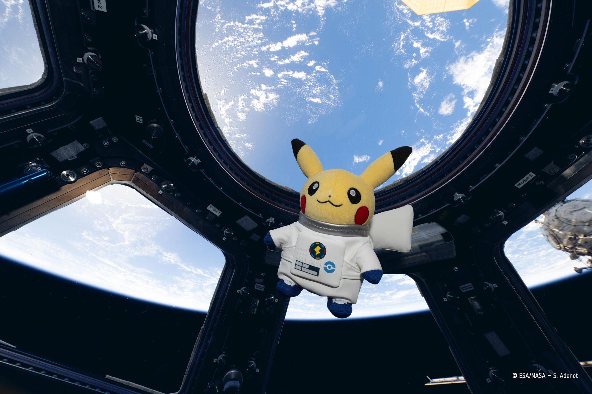 Astronaut Pikachu plush floating in the Cupola of the International Space Station
